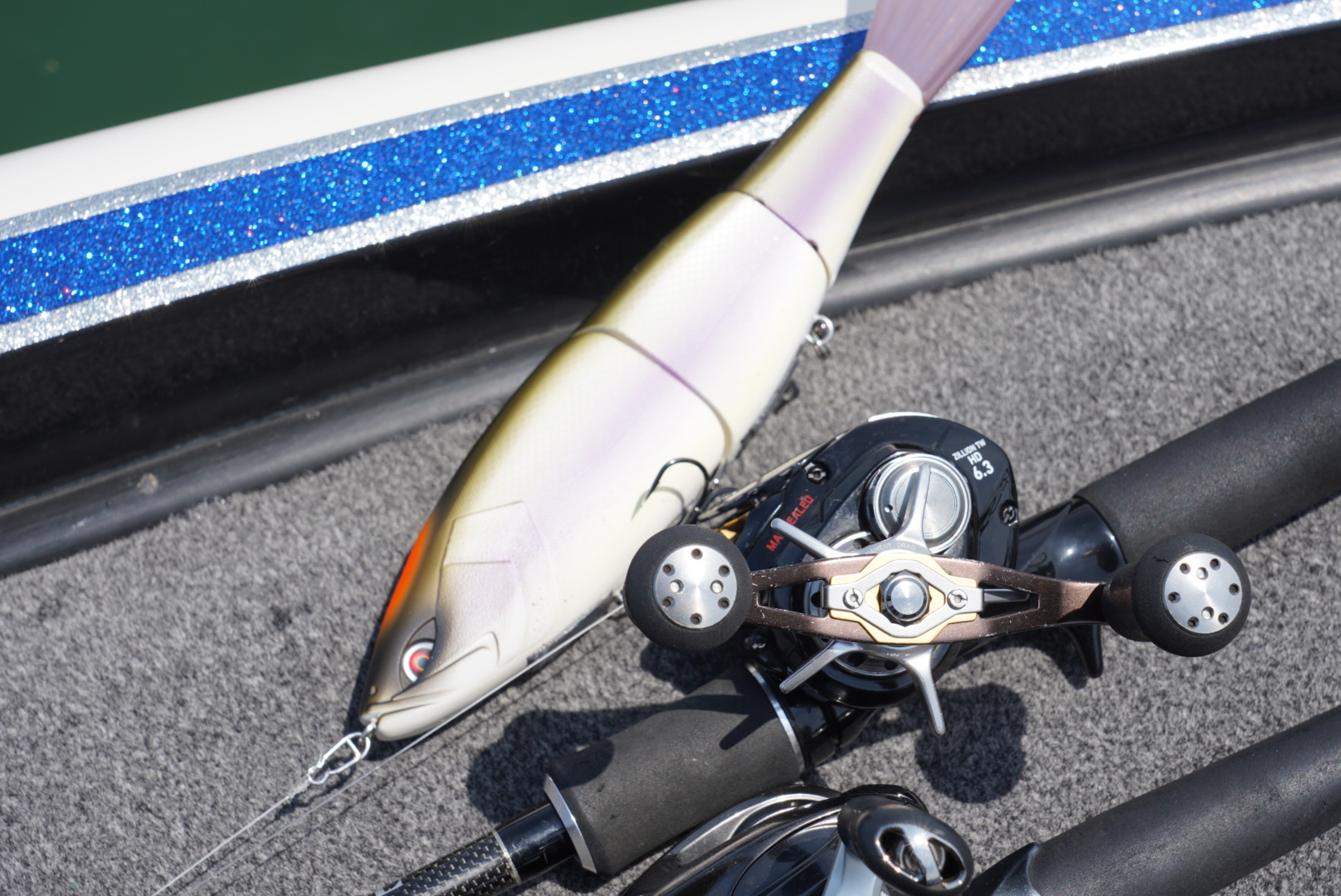 A large glide bait lure resting on a baitcasting reel and rod aboard a boat on Lake Biwa