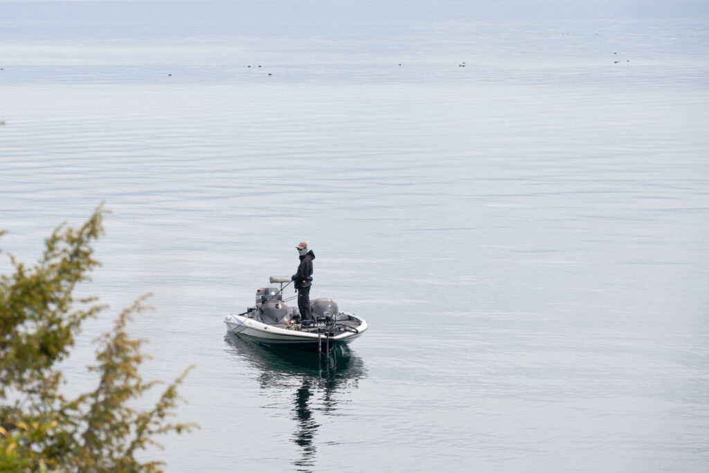 An angler standing on a bass boat using electronics on the calm, clear water of Lake Biwa's North Lake