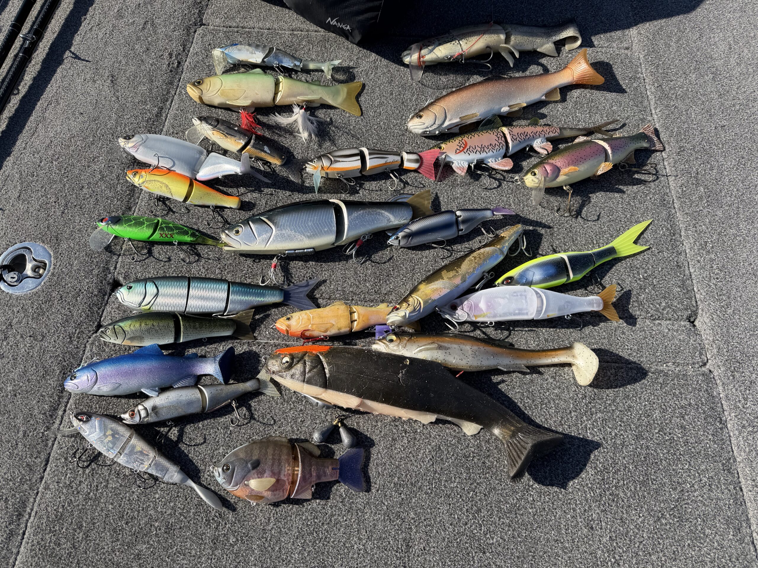 A large lineup of glide baits and swimbaits laid out on a boat deck at Lake Biwa