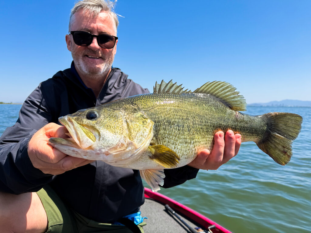 International guest holding a largemouth bass during a guided fishing trip on Lake Biwa