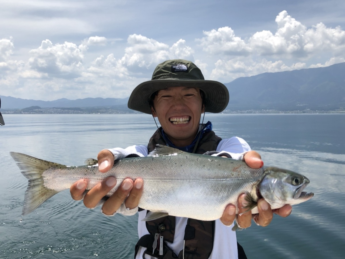 A smiling angler holding a Biwa trout on Lake Biwa