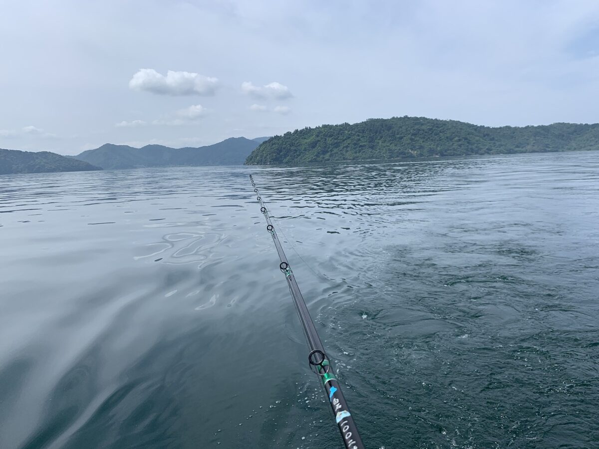 A trolling rod trailing a line across calm open water on Lake Biwa